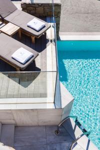 a patio area with a pool, chairs, and a pool table at Mykonos Beach Hotel in Mýkonos City