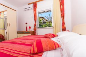 a bedroom with a bed with a red and white blanket at Apartments Katic in Trogir
