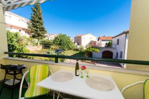 a balcony with a white table and chairs and a window at Apartments Katic in Trogir