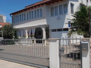 a white house with a gate and a fence at Apartments Adria in Jadrija