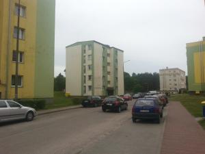 uma fila de carros estacionados numa rua com edifícios em Apartament Rega Mrzeżyno em Mrzeżyno