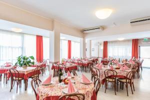 a restaurant with tables and chairs and red curtains at Hotel Seven in Rimini