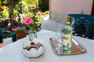 a table with a bottle of wine and a vase of flowers at Apartmani Anica in Risika