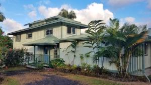 a house with a fence and palm trees in front of it at Hilo Vacation Rental in Hilo