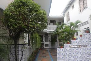 un edificio blanco con un árbol delante en El Patio Suites en Guayaquil