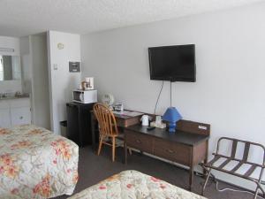 a hotel room with a bed and a desk with a television at Bonanza Gold Motel in Dawson City