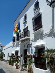 a white building with balconies and plants in front of it at Hostal Gran Capitan in Chipiona
