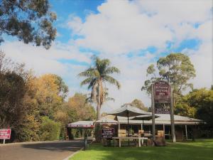 un restaurant avec un parasol et un palmier dans l'établissement Eltham Motor Inn, à Eltham