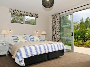 a bedroom with a bed and a large window at Flaxmill Accommodation in Whitianga