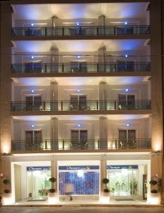 a three story building with two balconies at night at Olympic Star in Patra