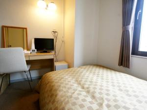 a bedroom with a bed and a desk with a computer at Hotel Trend Iwakuni in Iwakuni