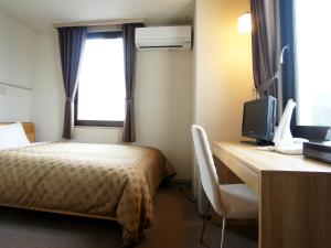 a hotel room with a bed and a desk with a television at Hotel Trend Iwakuni in Iwakuni