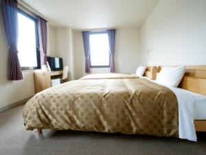 a bedroom with a large bed and two windows at Hotel Trend Iwakuni in Iwakuni