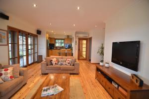 a living room with two couches and a flat screen tv at Stone Creek Cottage in Barwite