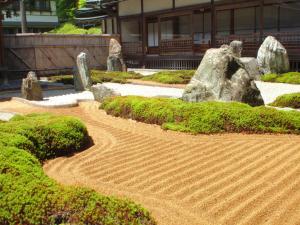 a garden with rocks and dirt in front of a building at Koyasan Onsen Fukuchiin in Koyasan