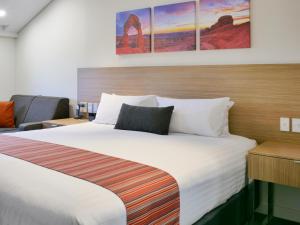 ein Hotelzimmer mit einem großen Bett mit weißen Laken in der Unterkunft Country Comfort Perth in Perth