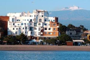 ジャルディーニ・ナクソスにあるスポーティング バイア ホテルの海辺の上に建つ白い大きな建物