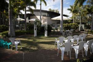 a group of white chairs and tables and palm trees at Capricorn Motel & Conference Centre in Rockhampton
