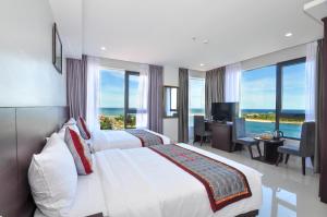 a hotel room with two beds and a desk and windows at Anh Linh 2 Hotel in Dong Hoi
