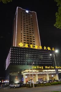 een hoog gebouw met 's nachts een bord bij Hui Fu Jinling Hotel in Gaoyou