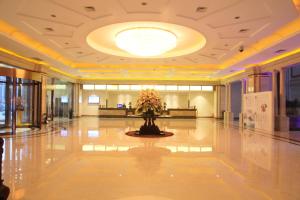 un vestíbulo con un jarrón de flores en el suelo en Hui Fu Jinling Hotel, en Gaoyou