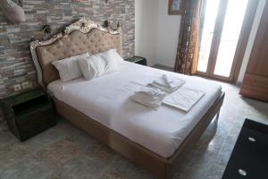 Una cama con sábanas blancas y toallas. en Orama Apartments, en Agia Anna de Naxos