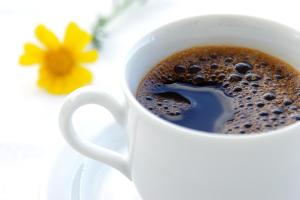 a cup of coffee with a flower in the background at Svenska Design Hotel in Mumbai