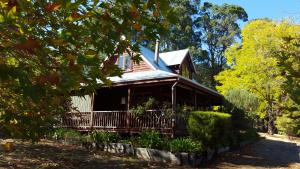 une maison brune avec une véranda et des arbres dans l'établissement Redgum Hill Country Retreat, à Balingup