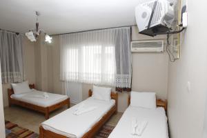 セルチュクにある ヴァルダル ペンションのベッド2台とテレビが備わる小さな客室です。