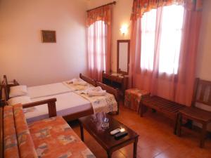 a room with two beds and a table and a mirror at Adonis Rooms in Skopelos Town