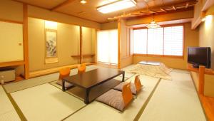 sala de estar con mesa, sillas y TV en Isawa View Hotel, en Fuefuki