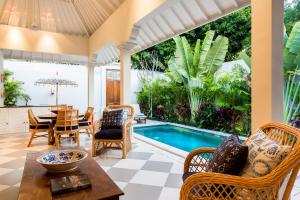 a living room with a table and chairs and a swimming pool at Villa Antiga 2 in Seminyak
