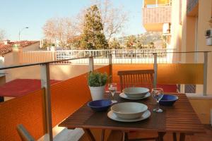 a wooden table with plates and wine glasses on a balcony at Laquilla II in Platja  d'Aro