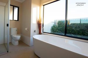 ein Badezimmer mit Badewanne und Toilette und einem Fenster in der Unterkunft Still Earth in Port Pirie + 26 Fotos