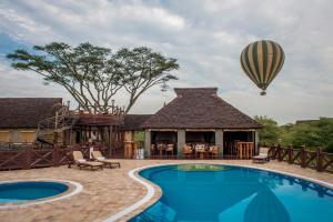 une montgolfière survolant une maison avec piscine dans l'établissement Lake Ndutu Luxury Tented Lodge, à Sinoni