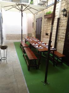 une longue table en bois avec des bancs et un parasol dans l'établissement B&B Cemener, à Ruvo di Puglia