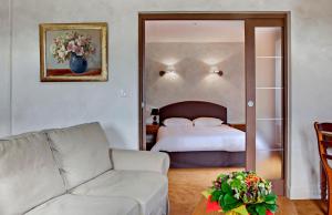 a living room with a bed and a couch at Hotel Beauséjour in Vic-sur-Cère