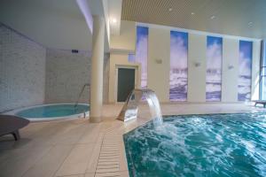 SeaPark Hotel Wellness & Spa في كولوبرزيغ: مسبح مع حوض استحمام ساخن في مبنى