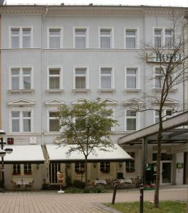 ein großes weißes Gebäude mit einem Baum davor in der Unterkunft Hotel Sächsischer Hof in Chemnitz