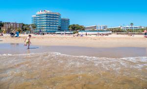 un niño pequeño parado en el agua en la playa en Golden Donaire Beach, en La Pineda