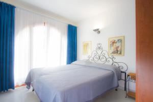 カポリーヴェリにあるAl Pozzo Residenceのベッドルーム1室(青いカーテン、窓付)