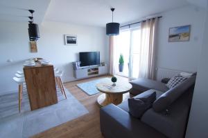 una sala de estar con un sofá y una mesa en Apartament Kropla Bałtyku 16 Darłówko, en Darłówko