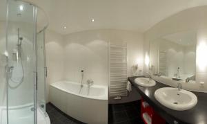 a bathroom with two sinks and a tub and a shower at Hotel zum Kirchenwirt Mariazell in Mariazell +45 photos