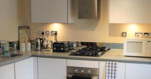 a kitchen with white cabinets and a stove and microwave at Canal Side in Worcester
