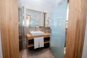 ein Badezimmer mit Waschbecken und Spiegel in der Unterkunft Loewe Dolomites in Innichen