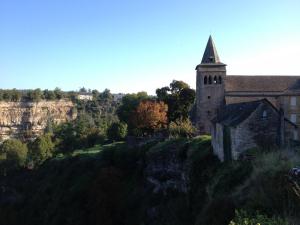 uma velha igreja ao lado de uma colina em Maison Del Traouc em Bozouls