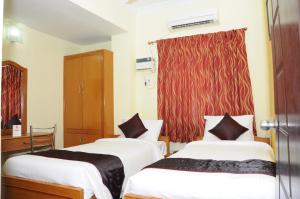 two beds in a room with a red curtain at Green Grande Inn in Chennai