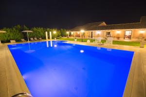 a large blue swimming pool at night at B&B Il Giardino di Sicilia in Case Monterosso
