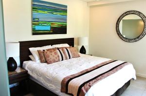 a bedroom with a bed and a mirror at 132 Temple Luxury Direct Studio in Port Douglas