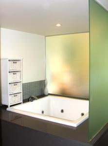 a bath tub in a bathroom with a green wall at 132 Temple Luxury Direct Studio in Port Douglas